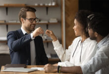 Real estate agent giving keys from new bought house own apartment to young excited couple