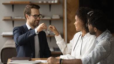 Real estate agent giving keys from new bought house own apartment to young excited couple